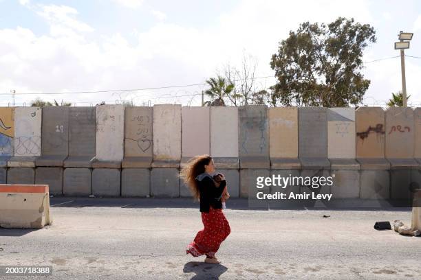 Young woman holding a baby walks barefoot as she is taking part in a protest that is blocking aid trucks entering the Gaza Strip at the Nitzana...