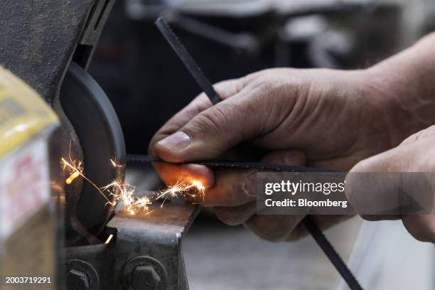 Worker uses a grinding wheel to repair a belt saw blade at the Usheco manufacturing facility in Kingston, New York, US, on Wednesday, Feb. 14, 2024....