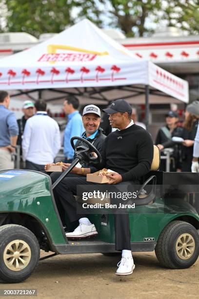 Tiger Woods stops to eat a burger from an In-N-Out food truck near the ninth tee box prior to The Genesis Invitational at Riviera Country Club on...