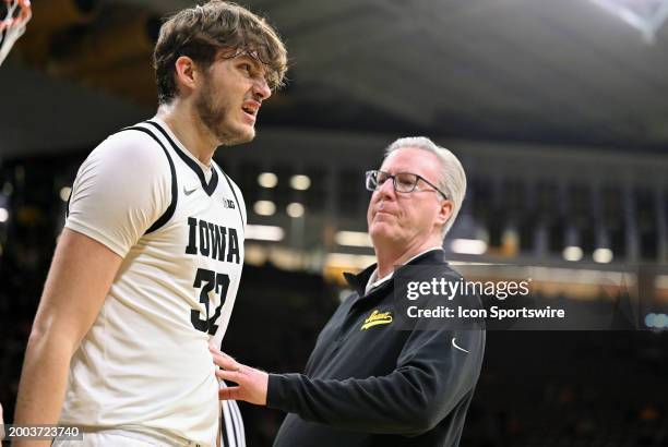 Iowa head coach Fran McCaffery checks over Iowa forward Owen Freeman after he chipped a tooth during a college basketball game between the Minnesota...