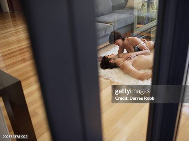 young couple embracing on rug, view through doorway - lech stock pictures, royalty-free photos & images
