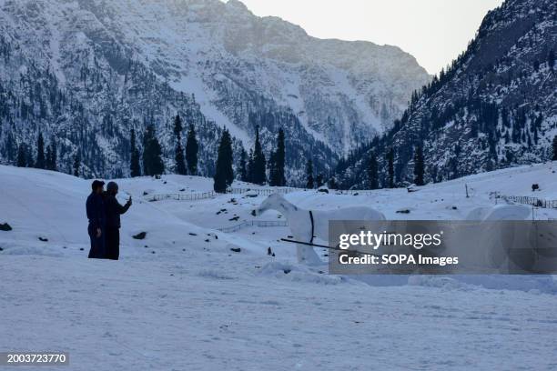 Visitors take photos of the Snow Horse Cart sculpture during a cold winter day in Sonamarg, about 100kms northeast of Srinagar, the summer capital of...