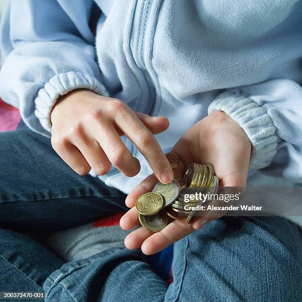 girl (8-10) counting coins in hand, close-up - zakgeld stockfoto's en -beelden