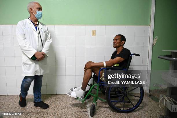 Doctor Alexey Lopez waits next to a patient before examining him in the cardiology room of the Calixto Garcia hospital in Havana on February 12,...