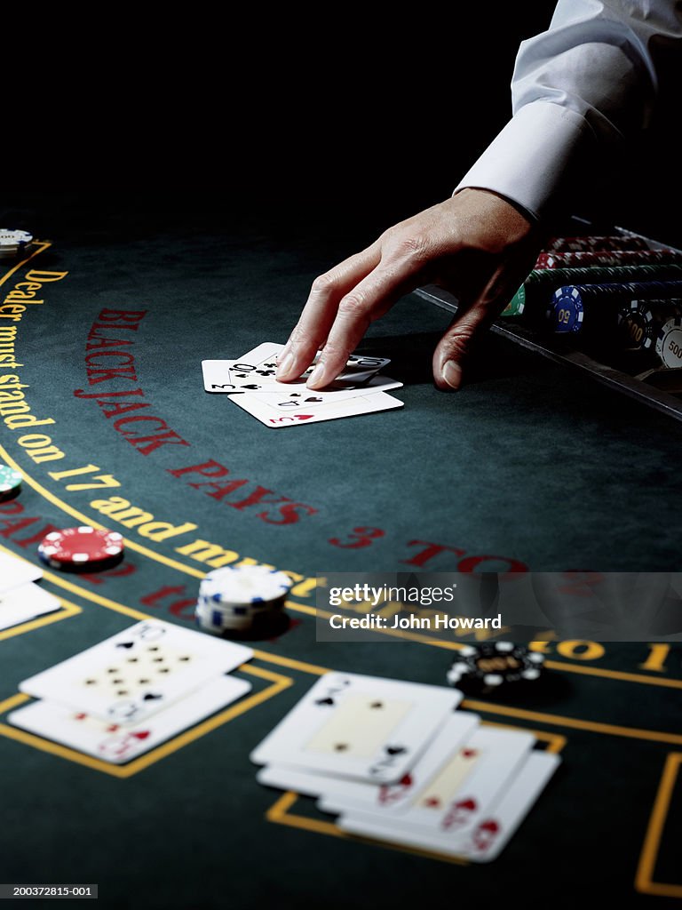 Male croupier resting hand on upturned cards on gaming table
