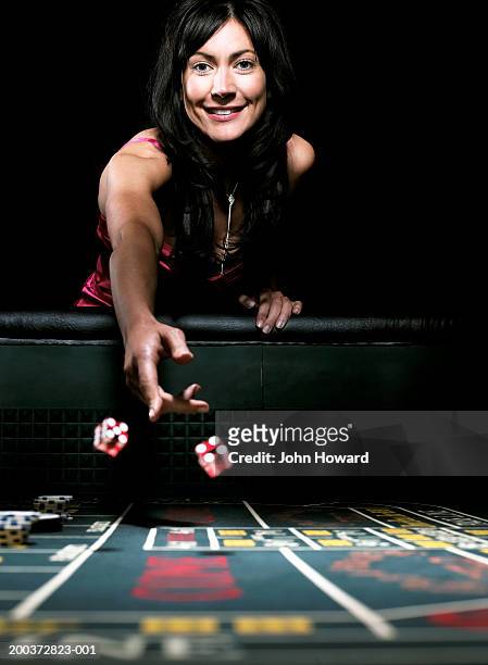 woman throwing dice on gaming table, smiling, portrait - casino elegance stock pictures, royalty-free photos & images