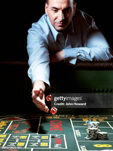 man leaning on gaming table throwing dice - casino dice stock pictures, royalty-free photos & images