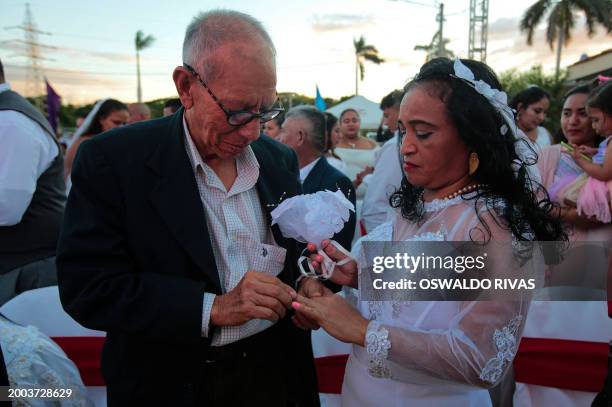 Rene Fonseca puts a wedding ring on his bride's finger, Flor de Maria Gutierrez during a free civil ceremony on Valentine's Day at Salvador Allende...