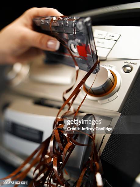 woman pulling tangled cassette tape out of hi-fi, close-up - cassette stock pictures, royalty-free photos & images