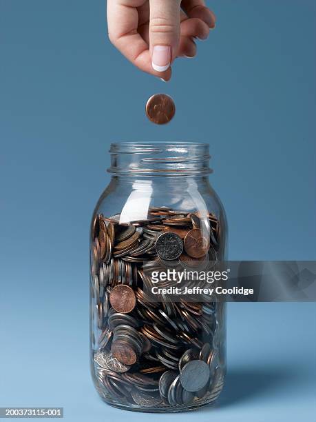 woman dropping coin into jar close-up - hands full stock pictures, royalty-free photos & images