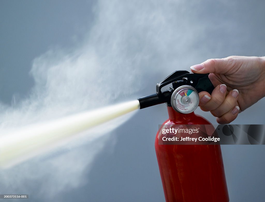 Woman using fire extinguisher, close-up