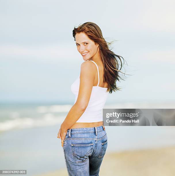 young woman looking over shoulder, smiling, portrait - tossing hair facing camera woman outdoors stock pictures, royalty-free photos & images