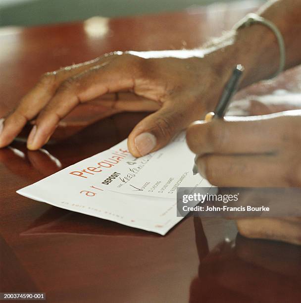 man filling out bank deposit slip. close-up - bank deposit slip stock-fotos und bilder