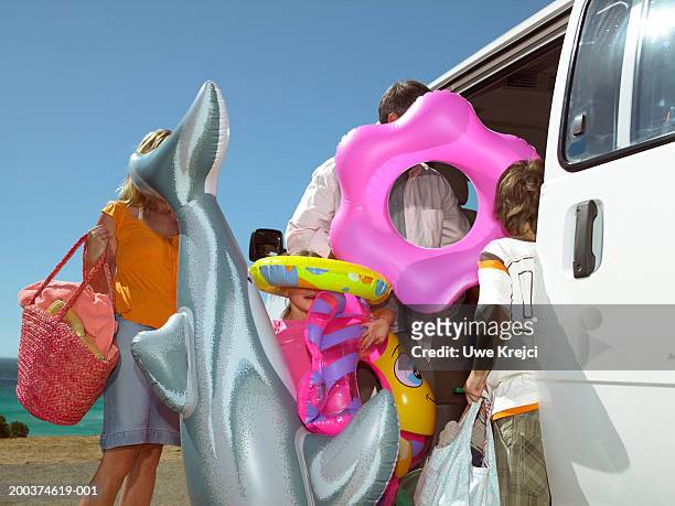 family holding inflatable toys by car outdoors - open day 9 bildbanksfoton och bilder