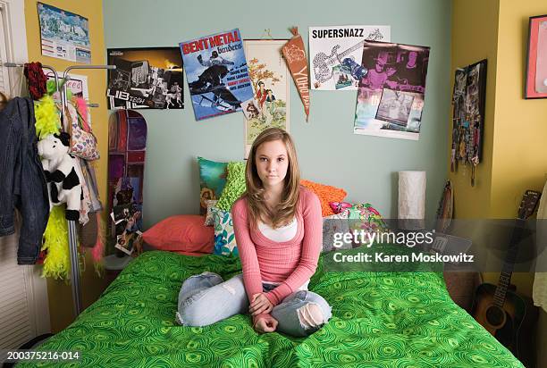 teenage girl (14-16) sitting on bed, portrait - bedroom wall stockfoto's en -beelden