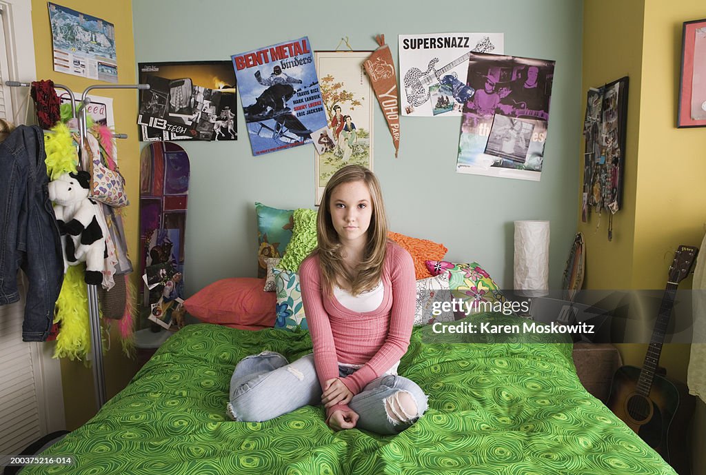 Teenage girl (14-16) sitting on bed, portrait