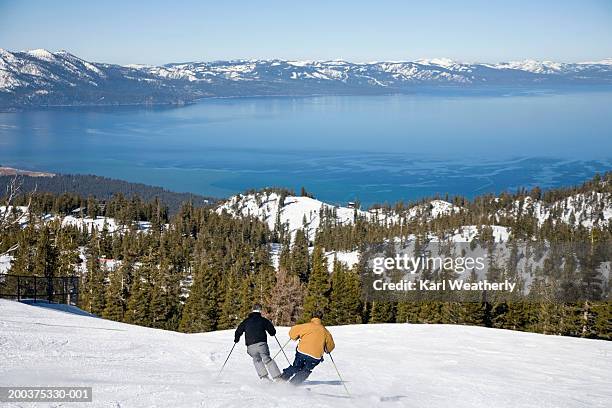 usa, california, lake tahoe, two men downhill skiing, rear view - see lake tahoe stock-fotos und bilder