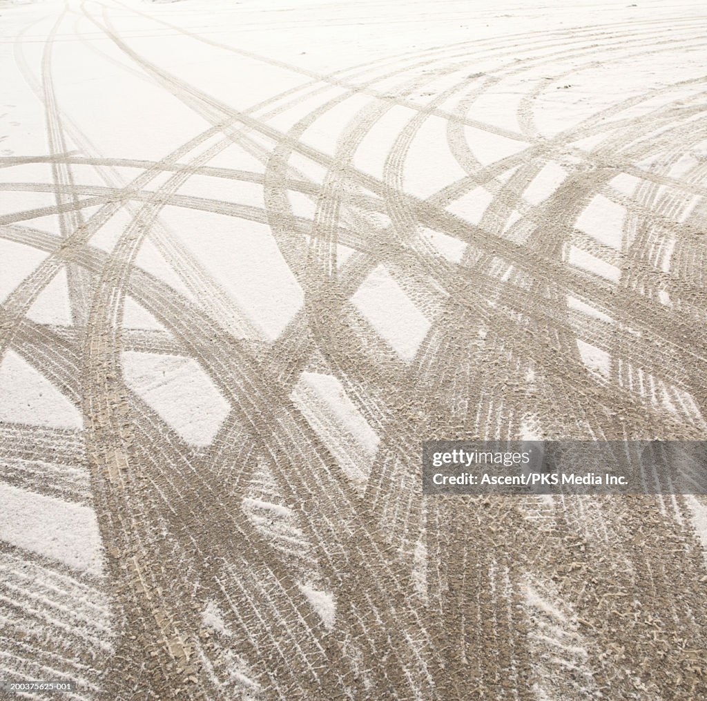 Multiple tire tracks in snow in parking lot