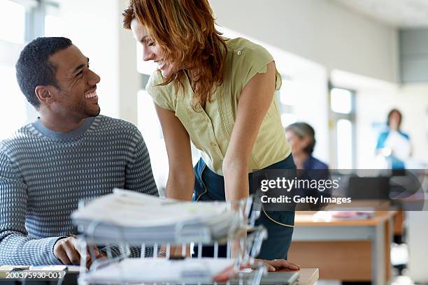 businessman and woman smiling at each other in office - romance de oficina fotografías e imágenes de stock