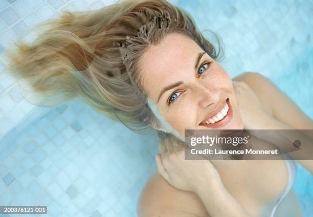 young woman relaxing in pool, face only above water, smiling, portrait - cabelo molhado imagens e fotografias de stock