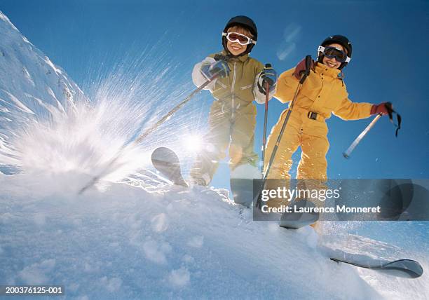 brother and sister (8-12) on ski slope, smiling, low angle view - female skier stockfoto's en -beelden