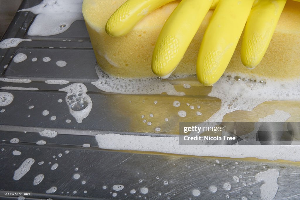 Rubber gloves and scrubbing pad on draining board, close-up