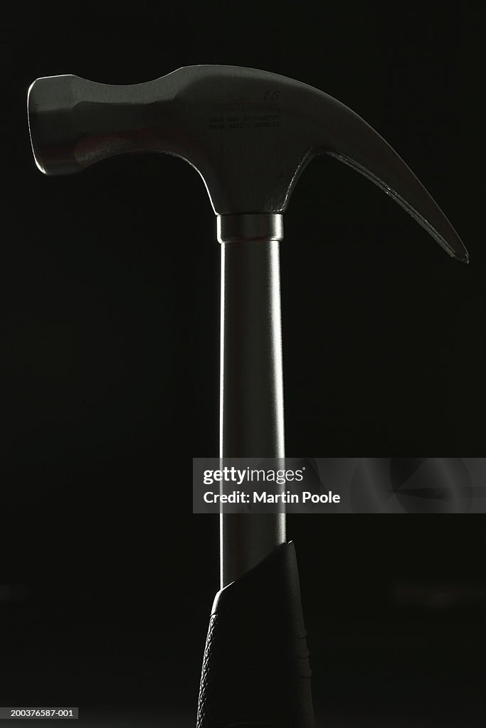 Hammer against black background, close-up (backlit)
