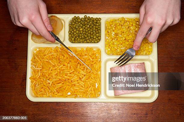 young man eating food off tray, overhead view, close-up of hands - tv dinner stock pictures, royalty-free photos & images