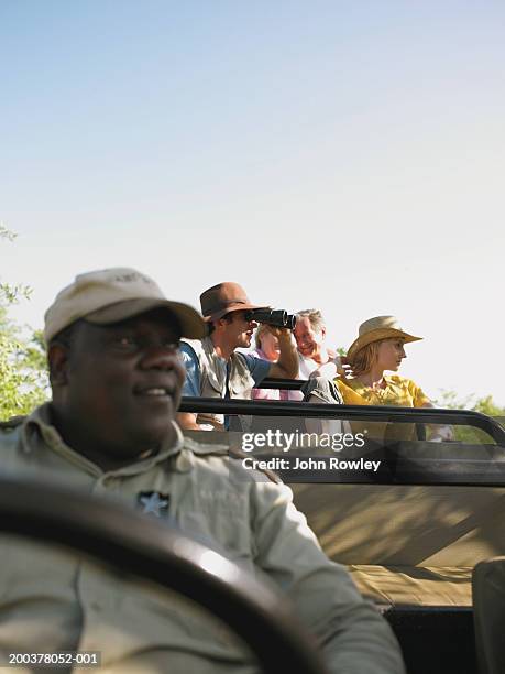 two couples on safari in 4x4, driver in foreground - africa safari watching stock pictures, royalty-free photos & images