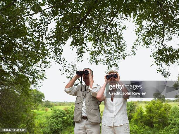 mature couple in landscape using binoculars - fågelskådning bildbanksfoton och bilder