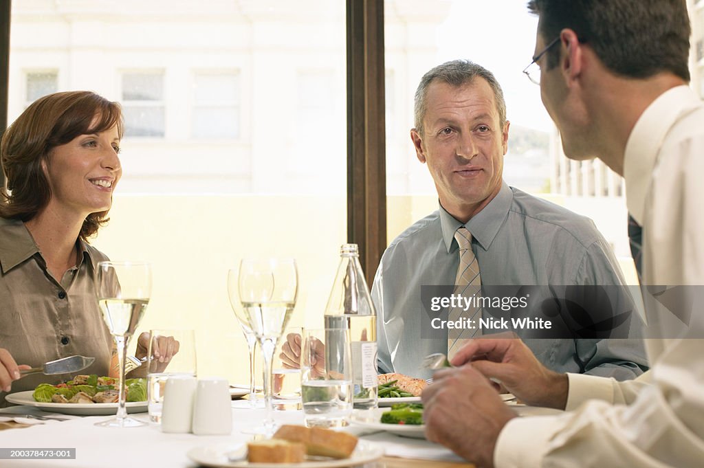 Two businessmen and woman at restaurant table