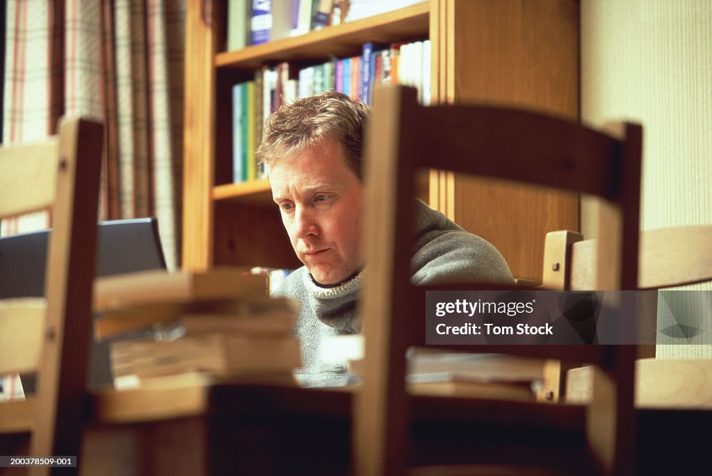 Mature man sitting at desk using laptop