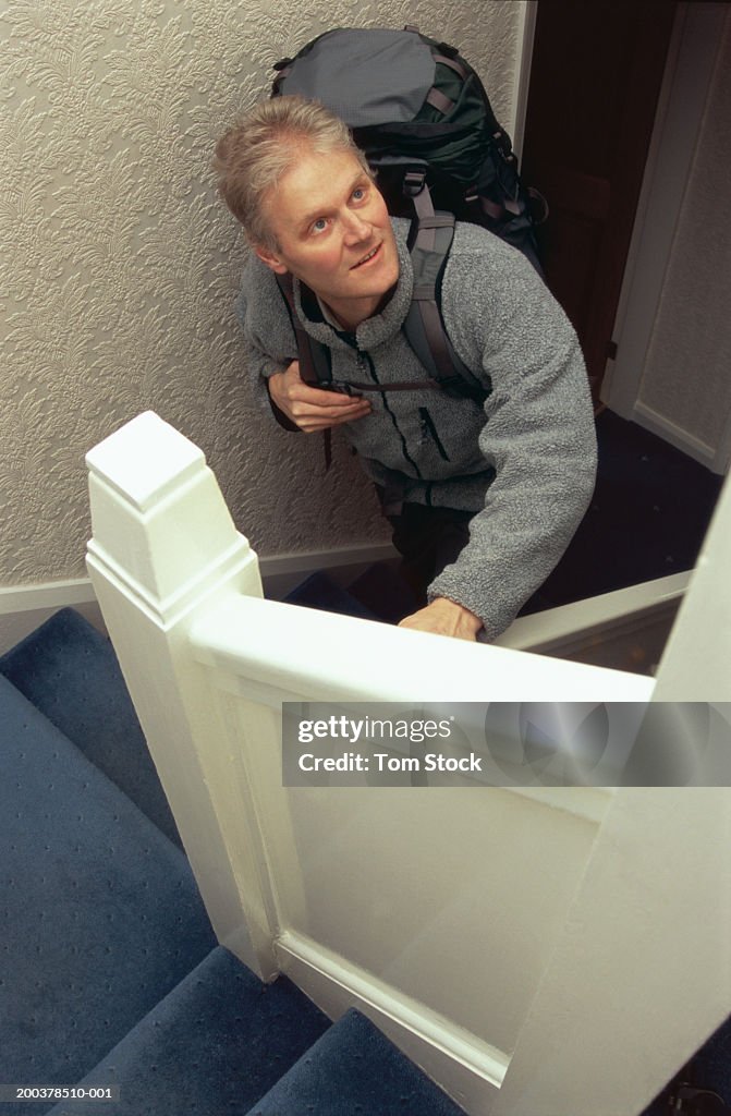 Mature man climbing stairs carrying rucksack, elevated view