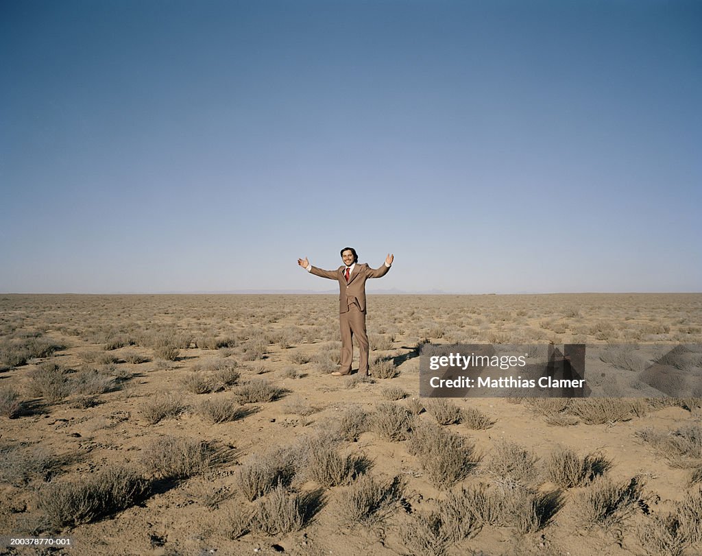 Businessman smiling in desert, portrait