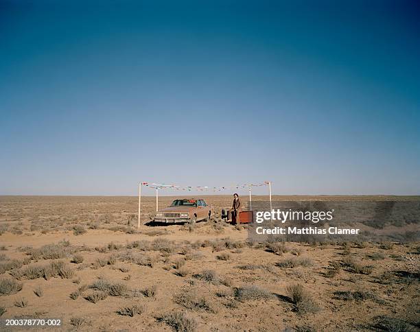 car salesman with car smiling in desert, portrait - auto sticker price stock pictures, royalty-free photos & images