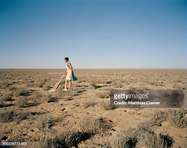 young woman vacuming in desert, side view - ironia imagens e fotografias de stock