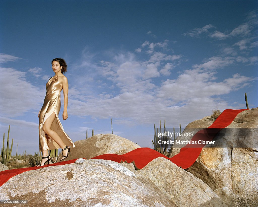 Young woman walking on red carpet laid on rocks