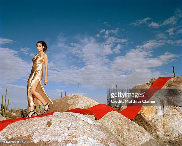 young woman walking on red carpet laid on rocks - satin dress 個照片及圖片檔