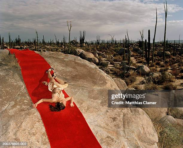 young woman lying on red carpet laid on rocks, elevated view - evening gowns stock pictures, royalty-free photos & images