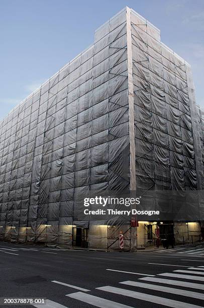 building covered in scaffolding and protective sheeting (wide angle) - baugerüst stock-fotos und bilder