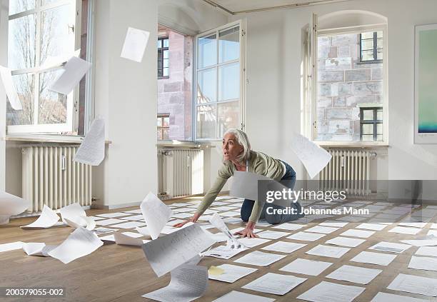 mature woman by papers blowing in wind indoors - top priority stock pictures, royalty-free photos & images