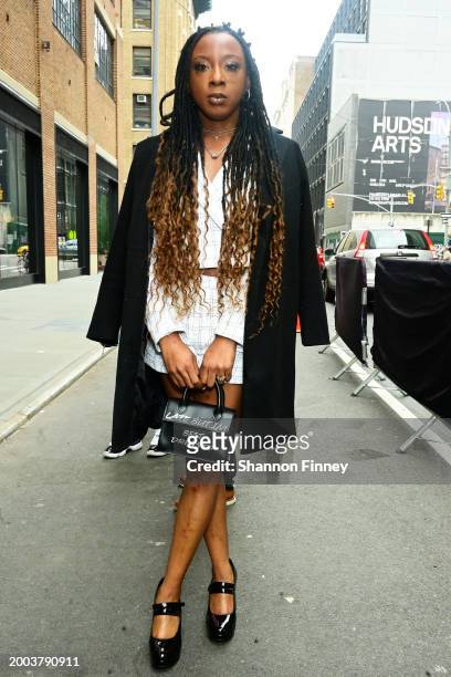 Guest wears a white shorts suit with a black walking coat, black patent leather mary jane pumps and a black mini satchel during New York Fashion Week...
