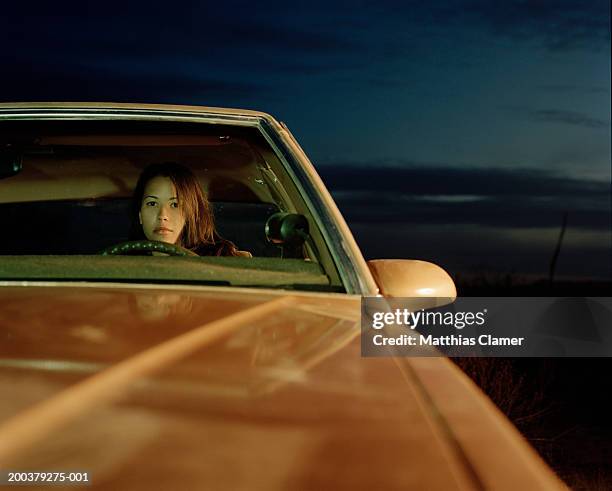 young woman sitting behind wheel of car, close-up - capô de carro imagens e fotografias de stock