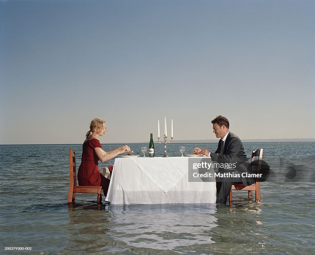 Couple having dinner in middle of ocean, side view