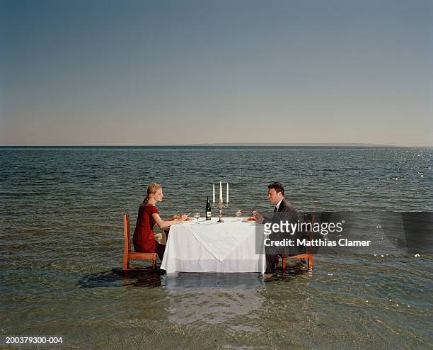 couple having dinner in middle of ocean, side view - alta marea foto e immagini stock