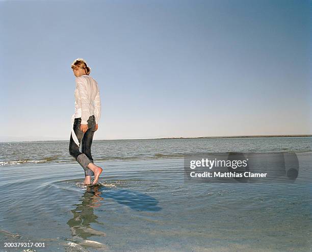 young woman walking in ocean, side view - ankle deep in water stock pictures, royalty-free photos & images