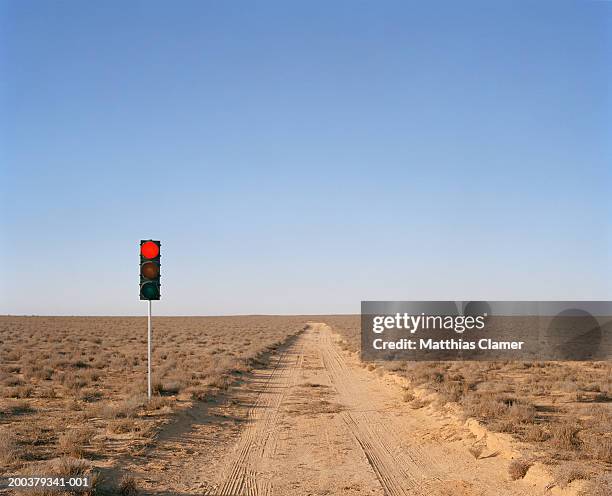 red traffic light on desert road - stoplight fotografías e imágenes de stock