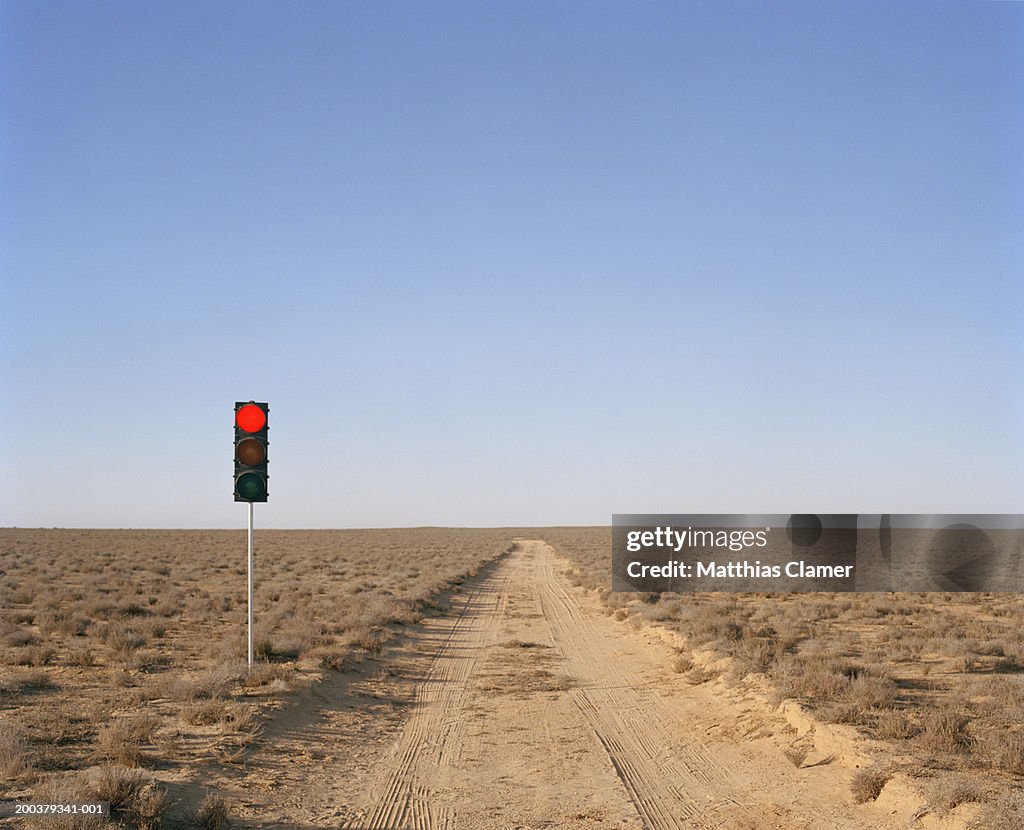 Red traffic light on desert road