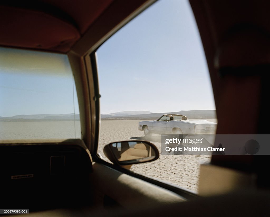 Two cars racing in desert, close-up