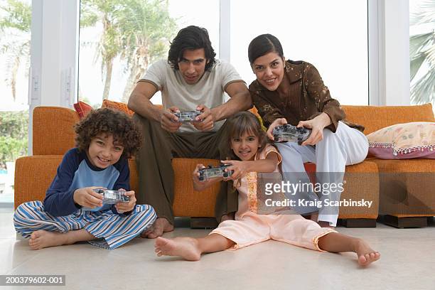 parents playing video game with son and daughter (7-9) smiling - game four stockfoto's en -beelden